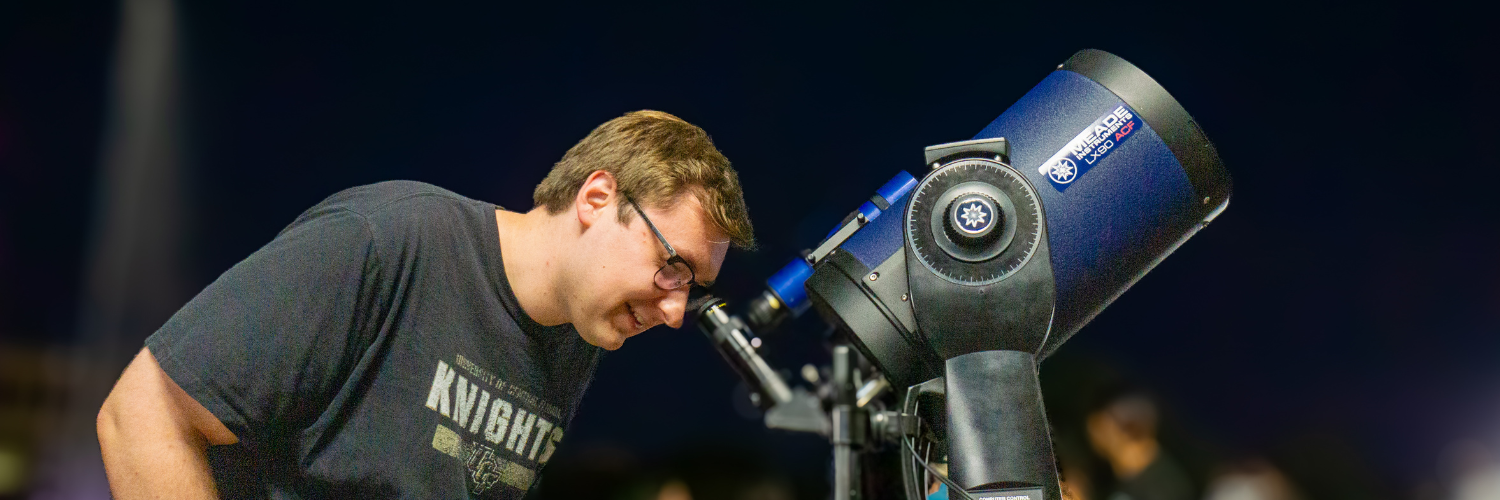 Person in UCF Knights t-shirt looking into telescope